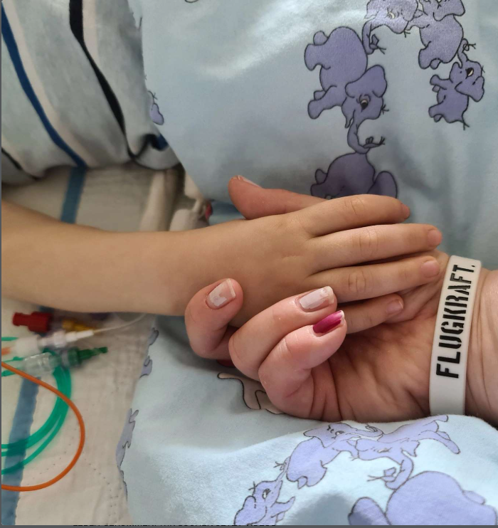 Zwei Hände im Krankenhaus als Zeichen von Nähe und Zusammenhalt.