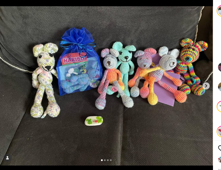 Mehrere gehäkelte Tiere und ein kleines Haribo-Päckchen liegen als Paket für die Pieksekisten auf einem Sofa.