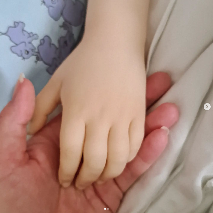 Eine kleine Hand liegt friedlich in einer erwachsenen Hand.