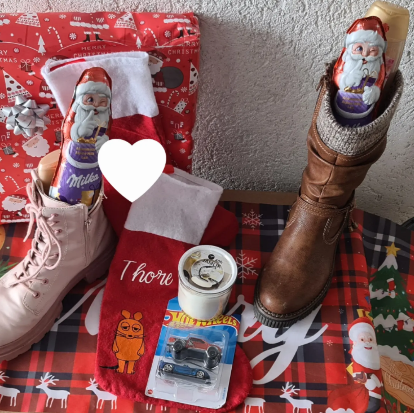 Nikolausstiefel, Geschenke und ein Nikolaus aus Schokolade liegen weihnachtlich dekoriert bereit.