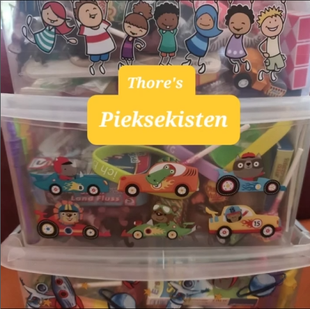 Transparente Kisten mit kleinen Spielzeugen und einem Schild Thore’s Pieksekisten.