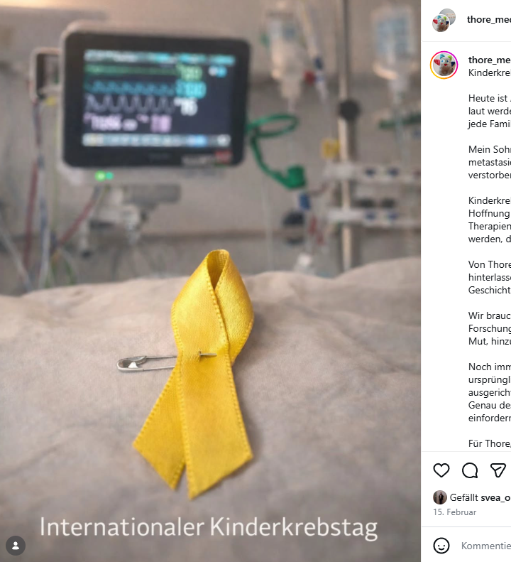 Eine gelbe Schleife liegt auf einem Krankenhausbett, im Hintergrund ist unscharf Medizintechnik zu sehen.